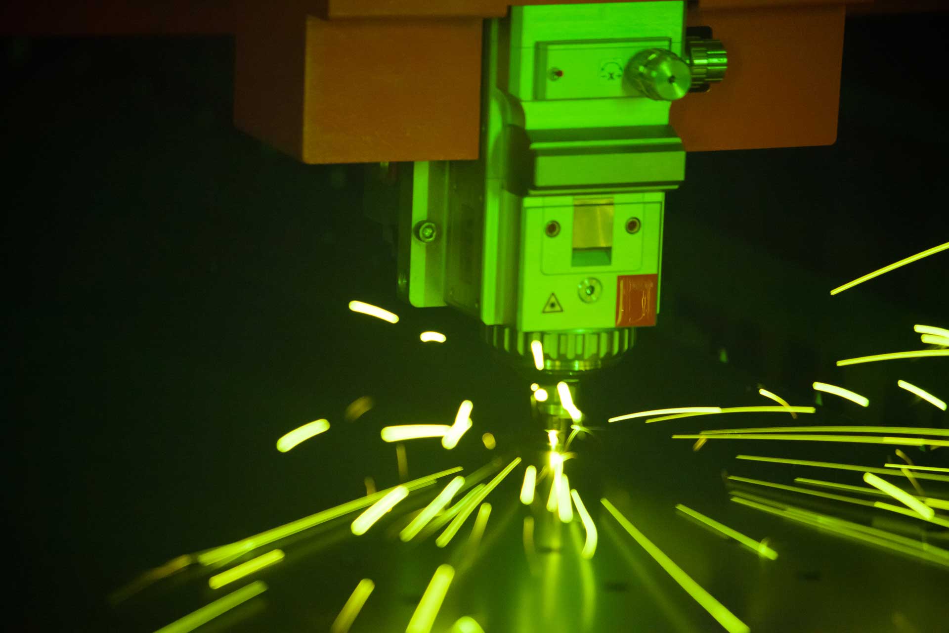 CNC machine cutting flat custom aluminum parts with sparks flying and a bright green cast. star's numerous careers offered. 
