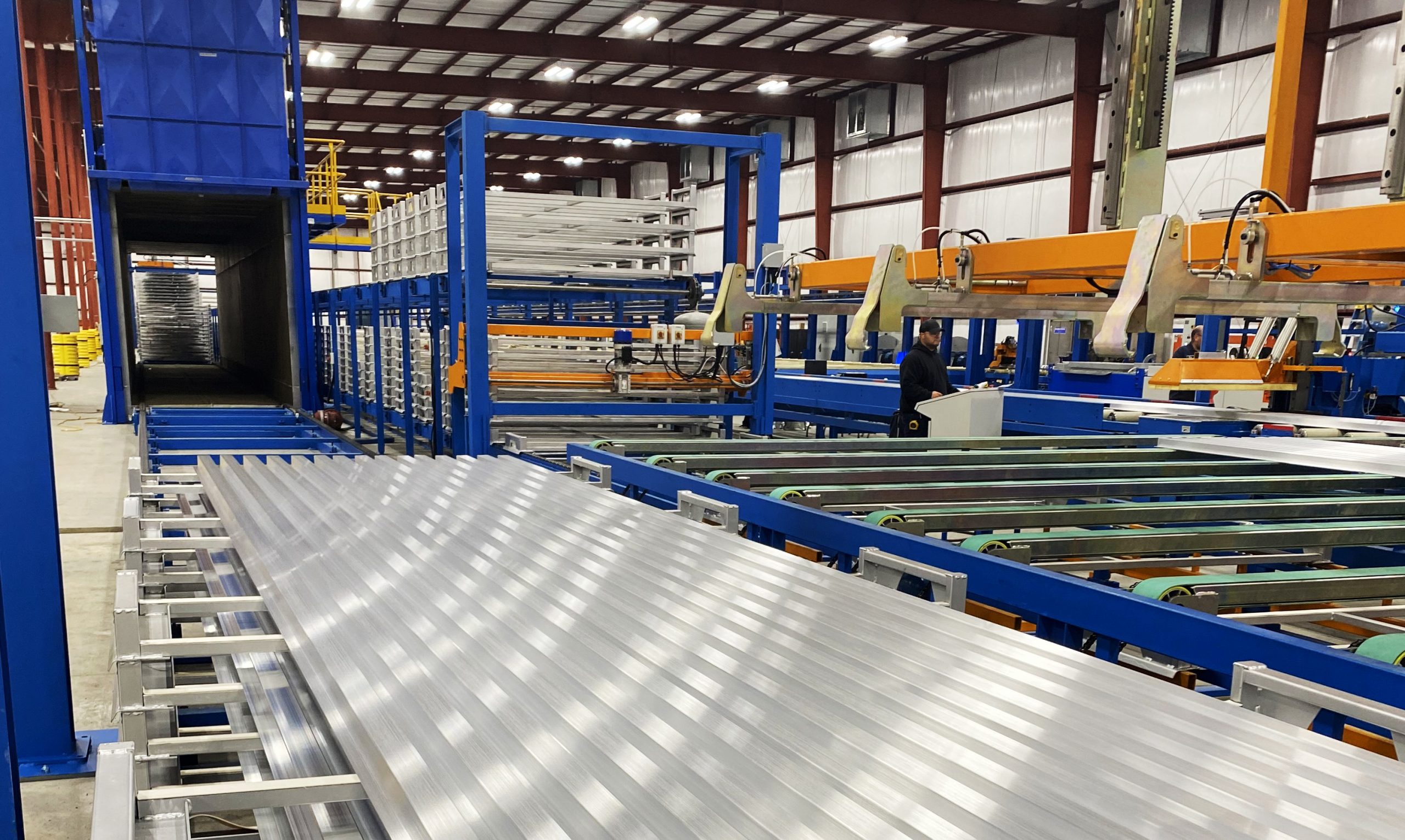 Numerous long aluminum extrusion pieces moving through the production line.