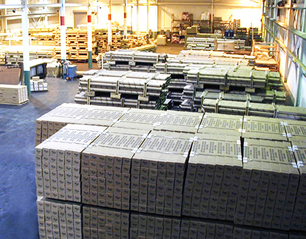 Wide shot of packaging and shipping department with stacks of boxes. 