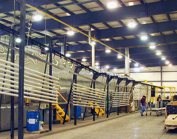 Aluminum extrusions hanging in the powder coating finishing line to dry.