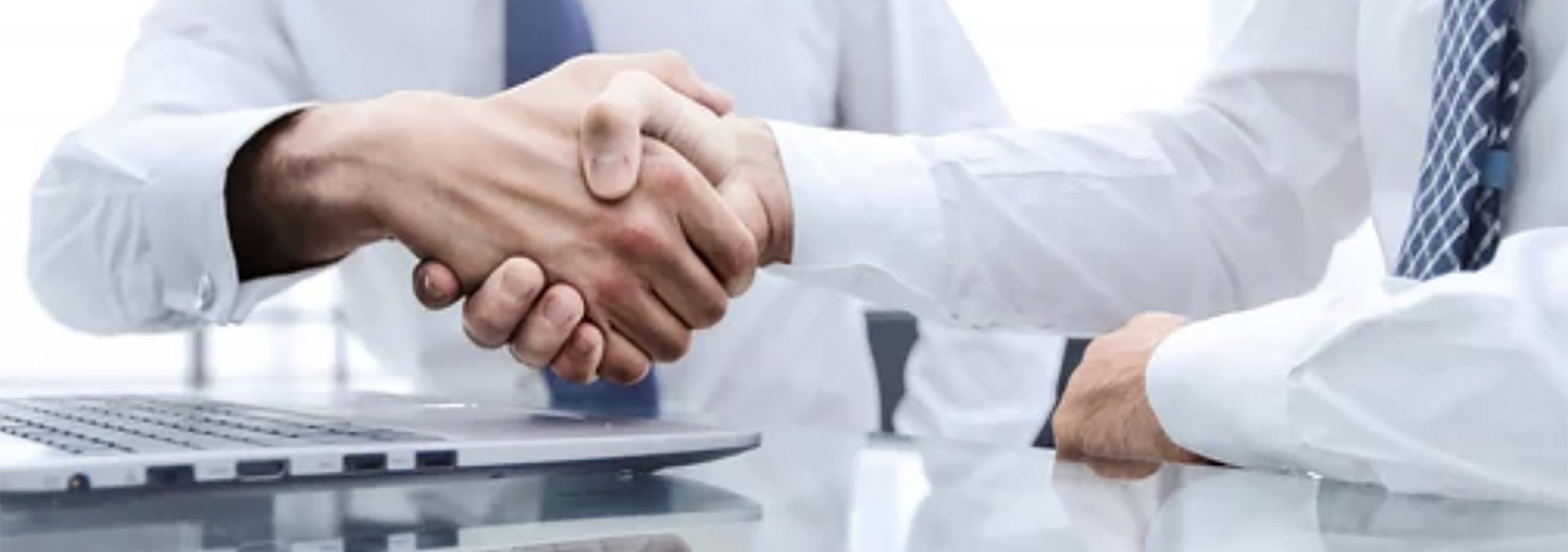 two people shaking hands over a desk.