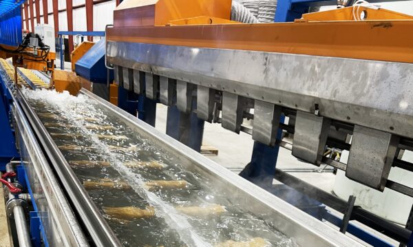 Aluminum extrusion being submerged in a water bath for cooling after exiting the press.