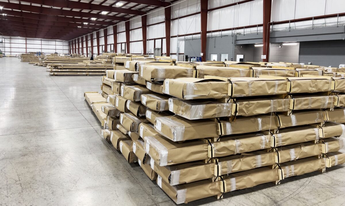 Wide angle picture of Star’s large packing and storage facilities. Large brown paper wrapped boxes sit stacked and lined up in a large warehouse space. 